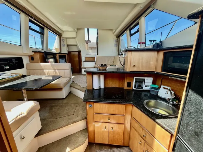  Yacht Photos Pics Interior of 2001 Carver 404 yacht with kitchen, seating, and stairs, featuring wood and black accents.