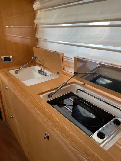 Yacht Photos Pics 2008 Absolute 47 HT yacht kitchen with stove and sink, featuring wooden cabinetry.