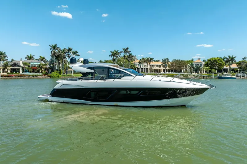 Midnight Oil Yacht Photos Pics 2018 Sunseeker Predator 57 yacht cruising on a sunny day, surrounded by palm trees.