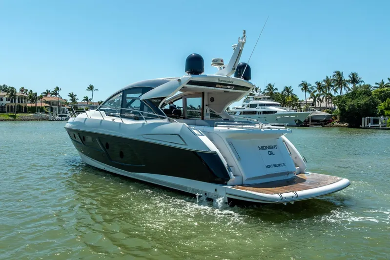 Midnight Oil Yacht Photos Pics 2018 Sunseeker Predator 57 yacht cruising on a sunny day near palm-lined shore.