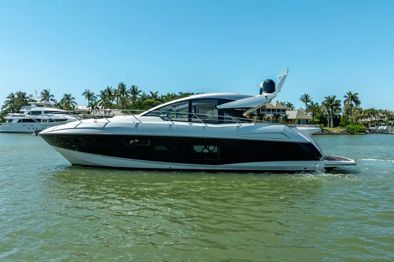 Midnight Oil Yacht Photos Pics 2018 Sunseeker Predator 57 yacht cruising on a sunny day, surrounded by palm trees.