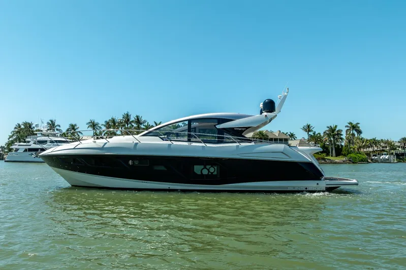 Midnight Oil Yacht Photos Pics 2018 Sunseeker Predator 57 yacht cruising on a sunny day, surrounded by palm trees.
