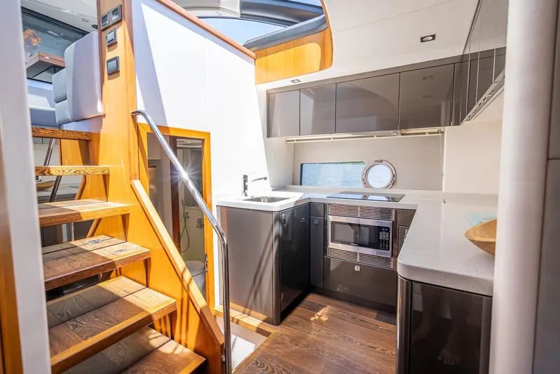 Midnight Oil Yacht Photos Pics Luxurious interior of 2018 Sunseeker Predator 57 yacht with modern kitchen and wooden stairs.