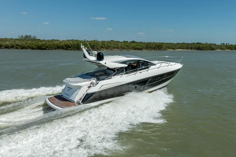 Midnight Oil Yacht Photos Pics 2018 Sunseeker Predator 57 yacht cruising on a sunny day, surrounded by calm waters.