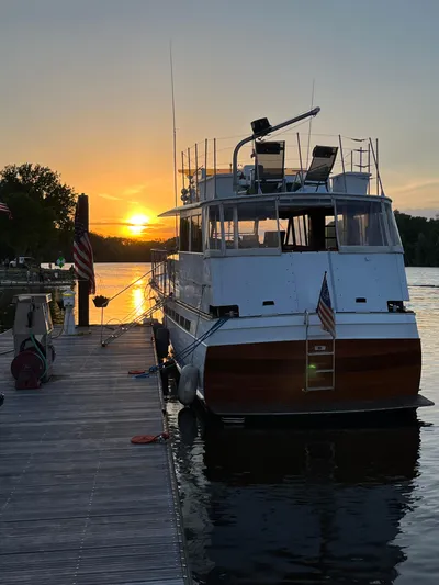  Yacht Photos Pics 1966 Chris-Craft 57 Constellation docked at sunset, reflecting on calm water.