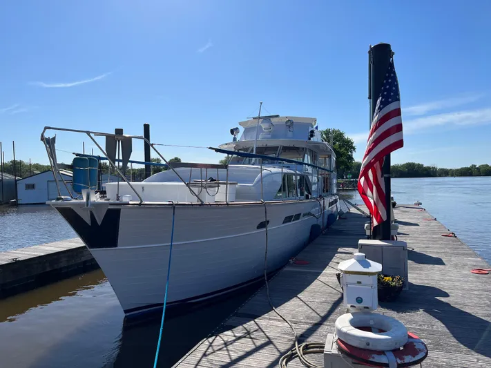  Yacht Photos Pics 1966 Chris-Craft 57 Constellation yacht docked beside an American flag on a sunny day.