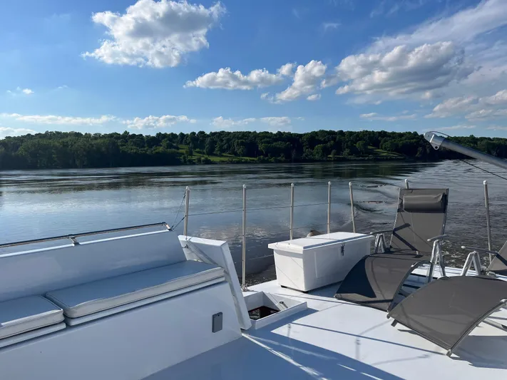  Yacht Photos Pics 1966 Chris-Craft 57 Constellation yacht deck with chairs, overlooking serene river and lush landscape.