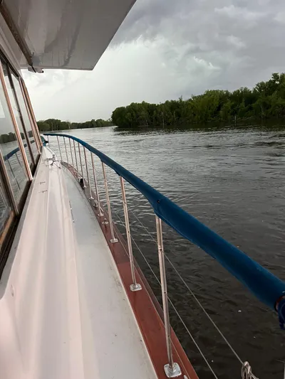  Yacht Photos Pics Side view of 1966 Chris-Craft 57 Constellation yacht on a river with cloudy sky.