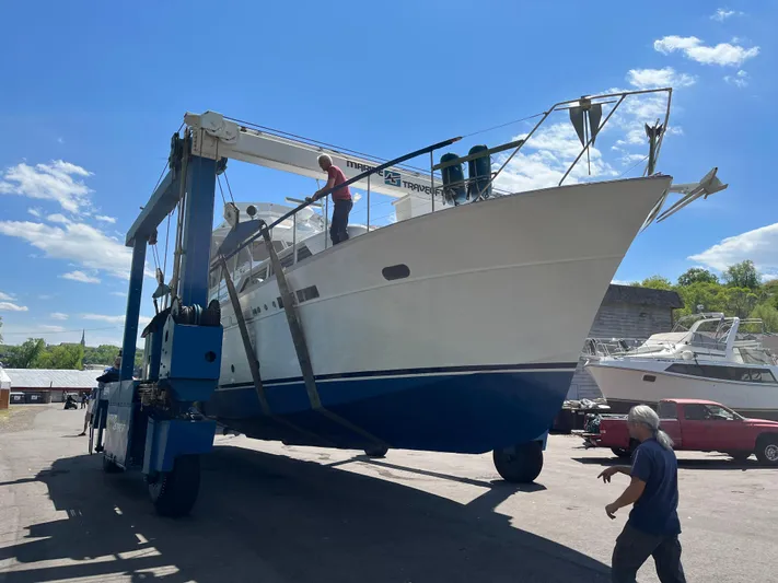  Yacht Photos Pics 1966 Chris-Craft 57 Constellation yacht being transported by a large lift under a clear blue sky.