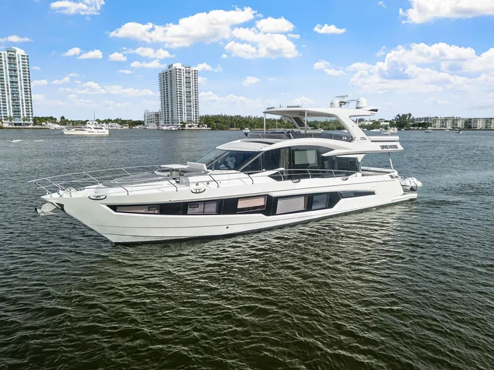 Live More Yacht Photos Pics 2021 Galeon 680 Fly yacht cruising on a sunny day with city skyline backdrop.