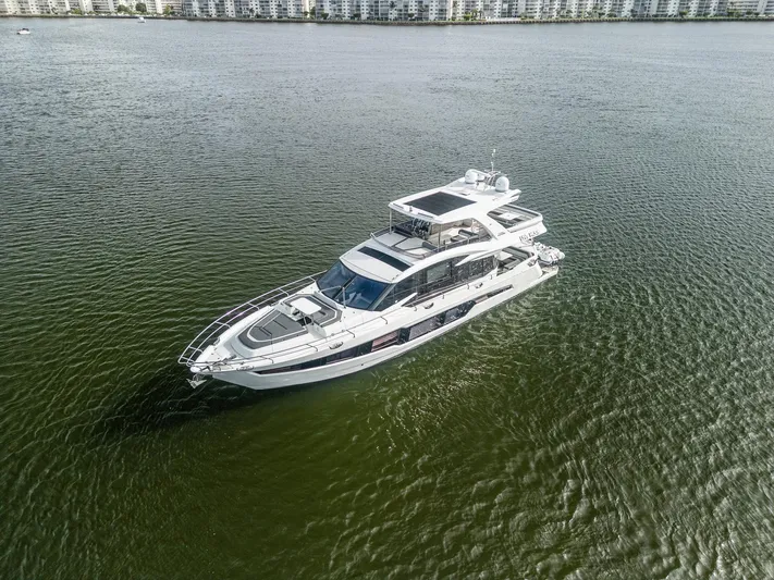 Live More Yacht Photos Pics 2021 Galeon 680 Fly yacht cruising on calm waters near a cityscape.