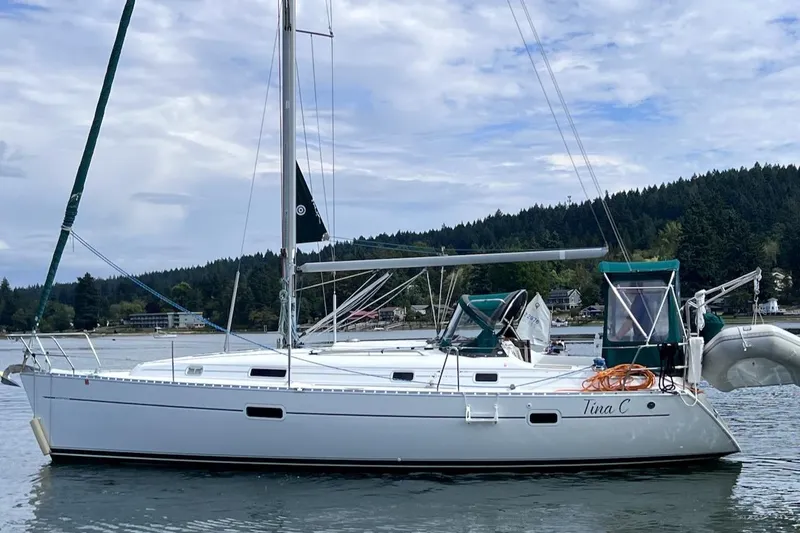 Tina C Yacht Photos Pics 2001 Beneteau 361 sailboat on calm water, surrounded by scenic forested shoreline.