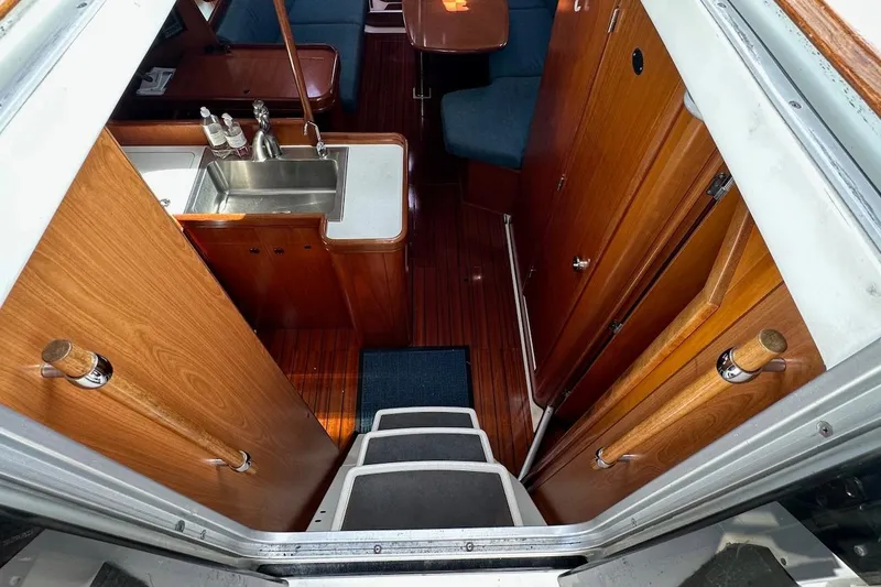 Tina C Yacht Photos Pics Interior view of 2001 Beneteau 361 sailboat, featuring wooden cabinetry and compact kitchen area.