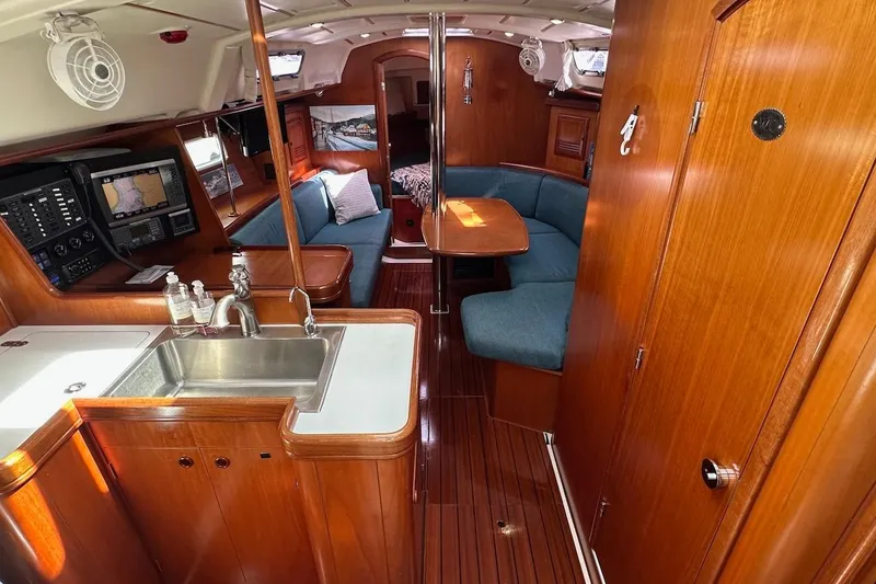 Tina C Yacht Photos Pics Interior of 2001 Beneteau 361 sailboat with wood finish and blue seating.