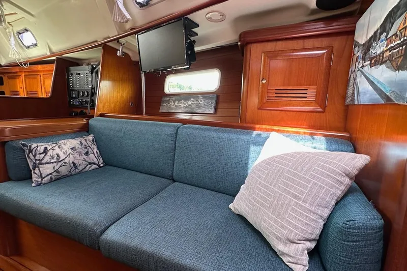 Tina C Yacht Photos Pics Interior of 2001 Beneteau 361 sailboat with blue sofa and wooden cabinetry.