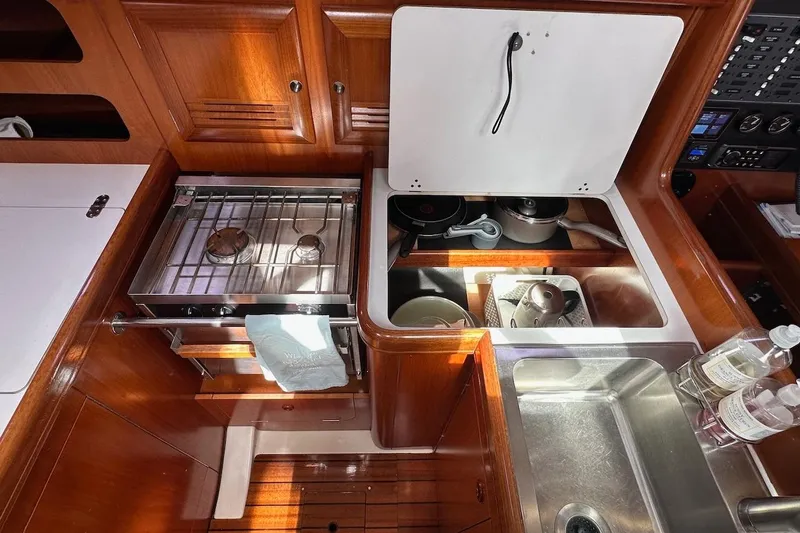 Tina C Yacht Photos Pics 2001 Beneteau 361 yacht kitchen with stove, sink, and wooden cabinetry.