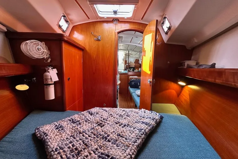 Tina C Yacht Photos Pics Interior of 2001 Beneteau 361 sailboat cabin with cozy bedding and wooden finish.