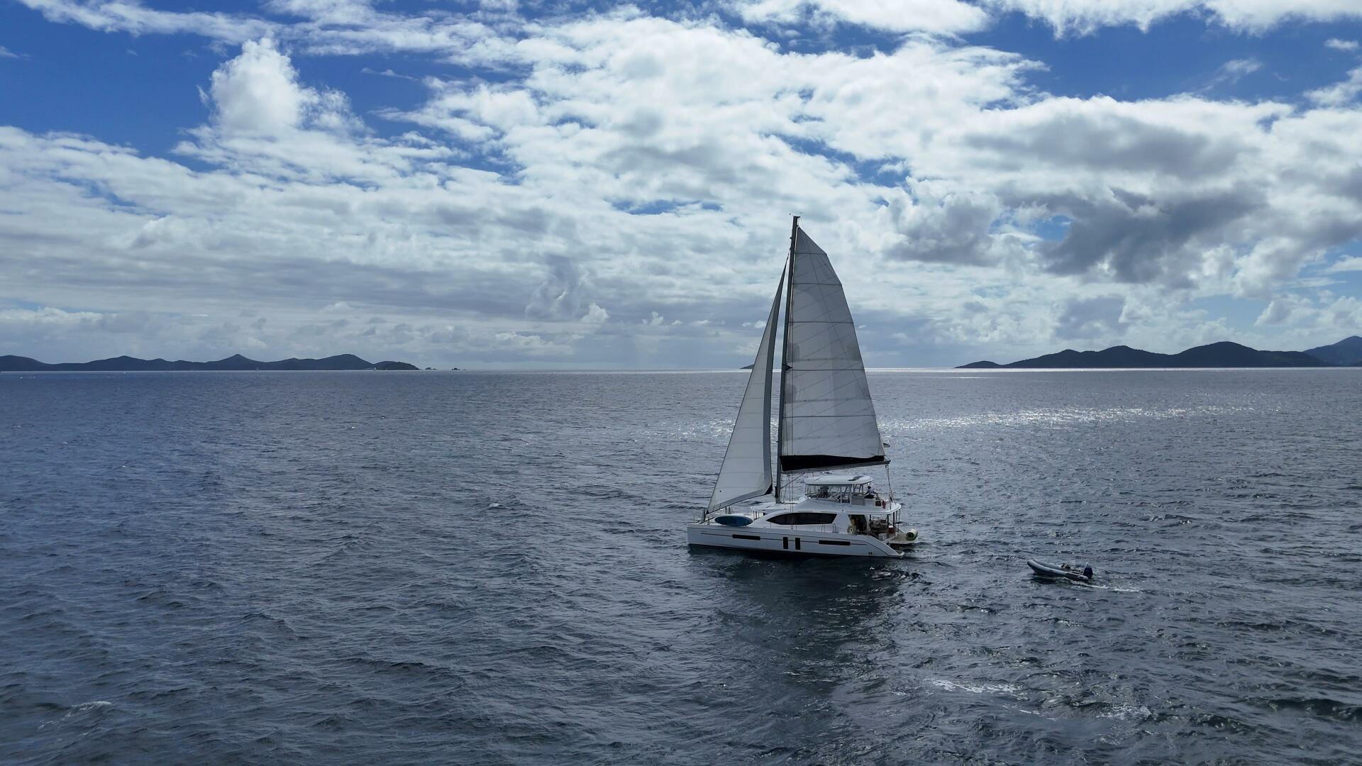 Sailing catamaran Leopard 58 on open sea under cloudy sky, 2016 model.