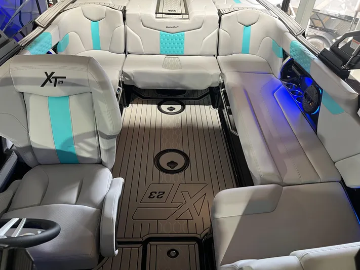  Yacht Photos Pics 2025 MasterCraft XT23 boat interior with gray and teal seating, illuminated accents, and stylish flooring.