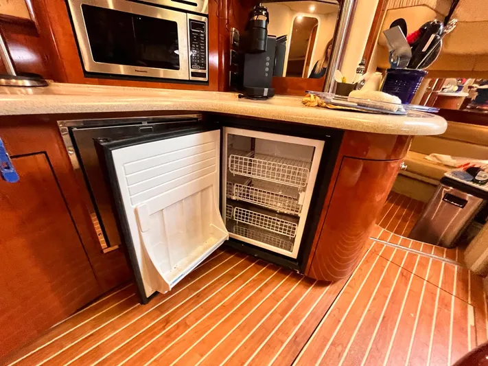 At Last Yacht Photos Pics 2004 Sea Ray 420 Sundancer yacht kitchen with open fridge, microwave, and wooden flooring.