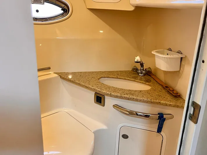 At Last Yacht Photos Pics Bathroom interior of 2004 Sea Ray 420 Sundancer with granite countertop and oval window.