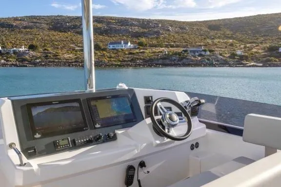  Yacht Photos Pics 2023 Leopard 46 Powercat helm with dual screens, steering wheel, and scenic coastal view.