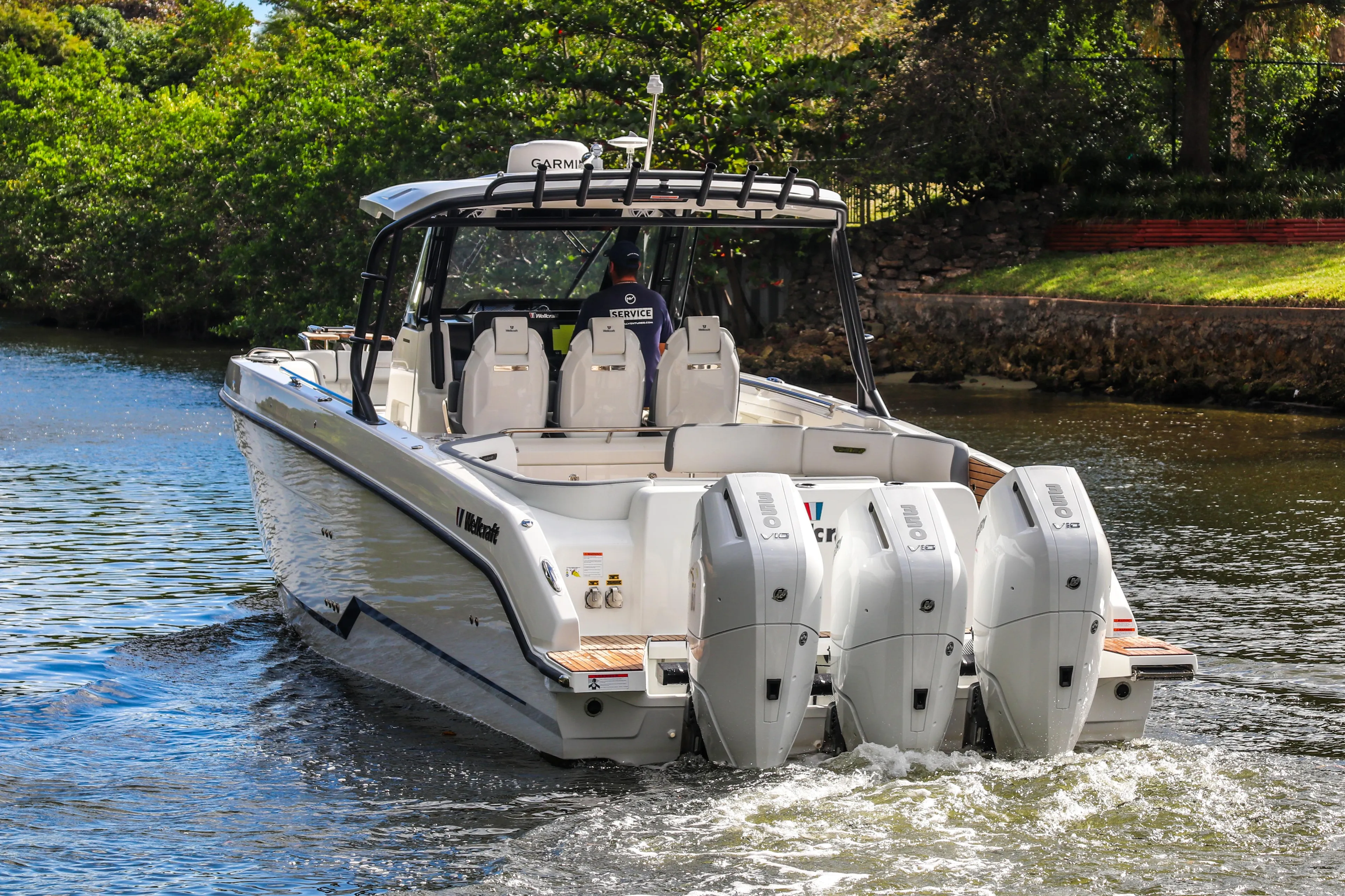 2026 Wellcraft 38 T-Top boat cruising on a scenic waterway.