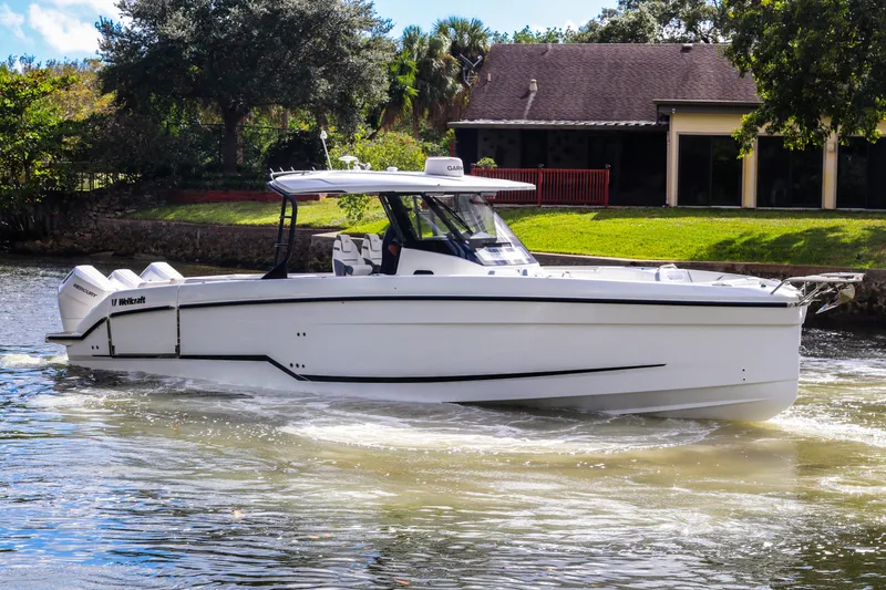  Yacht Photos Pics 2026 Wellcraft 38 T-Top boat cruising on a sunny day near a house.