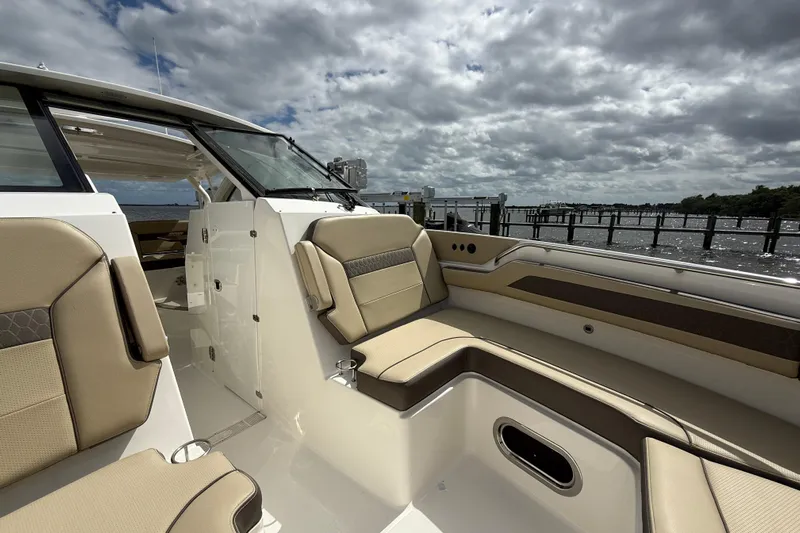  Yacht Photos Pics 2019 Pursuit DC 365 Dual Console boat interior with beige seating, dockside view.