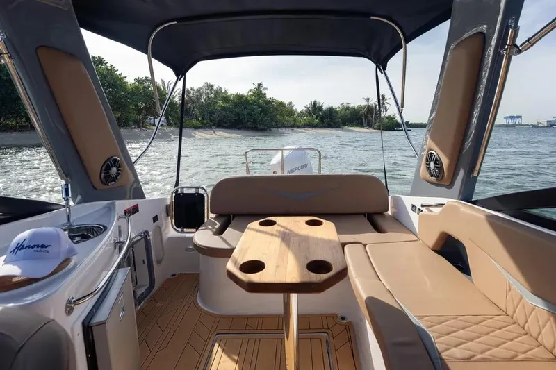  Yacht Photos Pics Interior view of 2025 Hanover 255 boat with seating and table, overlooking water and shoreline.