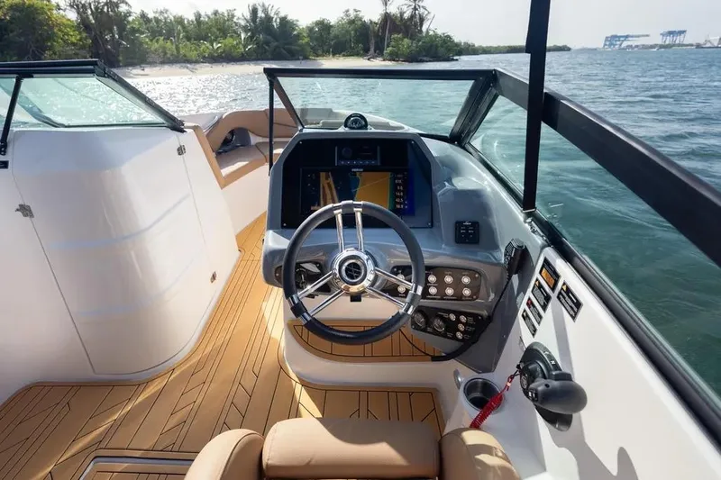  Yacht Photos Pics 2025 Hanover 255 boat interior with modern dashboard and steering, near a scenic shoreline.
