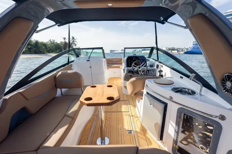  Yacht Photos Pics Luxurious 2025 Hanover 255 boat interior with seating, table, and helm, docked near a tropical island.