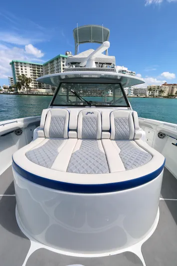 Alegria Yacht Photos Pics 2021 Yellowfin 54 Offshore boat with luxurious seating, docked near waterfront buildings.