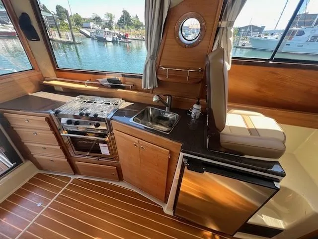 Red Diver Yacht Photos Pics 2022 Ranger Tugs R-29 S interior kitchen with stove, sink, and refrigerator.