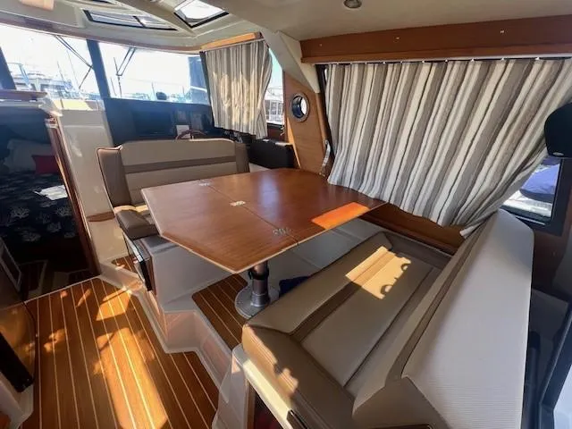 Red Diver Yacht Photos Pics 2022 Ranger Tugs R-29 S interior with dining area, wood table, and striped curtains.