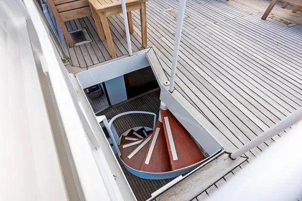Chanticleer Yacht Photos Pics Spiral staircase on a 1973 Burger 310C yacht with wooden deck and outdoor seating.