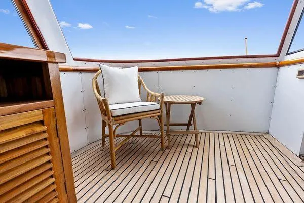 Chanticleer Yacht Photos Pics 1973 Burger 310C yacht deck with wooden chair and table, under a clear blue sky.