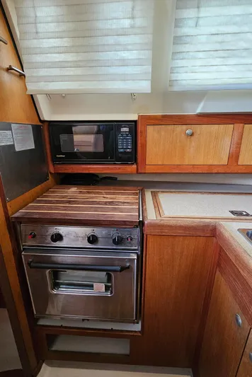  Yacht Photos Pics 1998 Hunter 340 Sloop kitchen with stove, microwave, and wooden cabinetry.