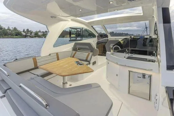 My Angel Yacht Photos Pics 2023 Beneteau Gran Turismo 32 yacht interior with seating and table on a calm lake.