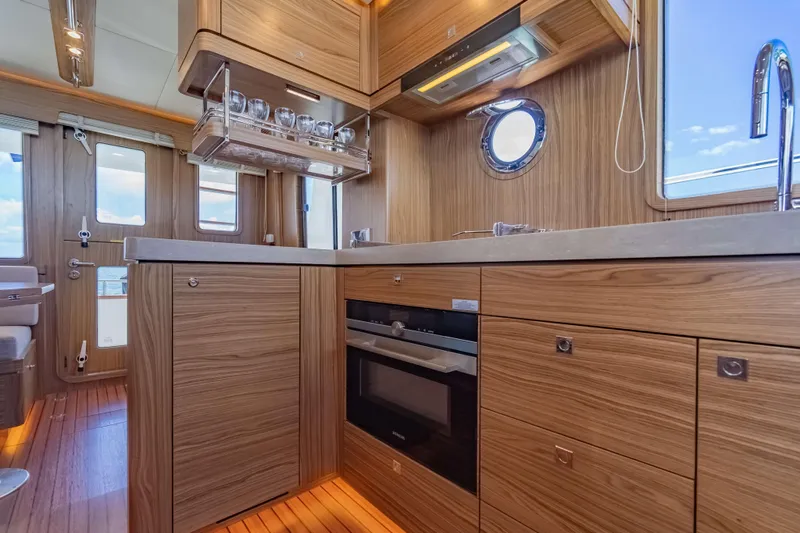Nordhavn 41 Yacht Photos Pics Modern kitchen interior of 2023 Nordhavn 41 yacht with wood cabinetry and porthole window.