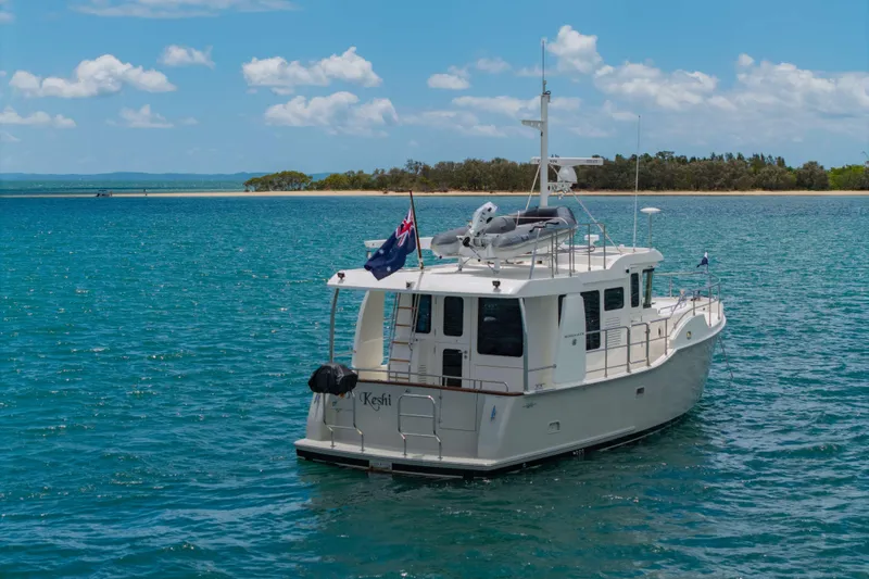 Nordhavn 41 Yacht Photos Pics 2023 Nordhavn 41 yacht on blue water near a sandy shoreline under a clear sky.
