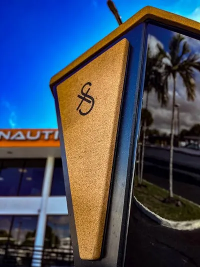  Yacht Photos Pics Close-up of 2023 X Shore Eelex 8000 boat emblem with palm trees and building in background.