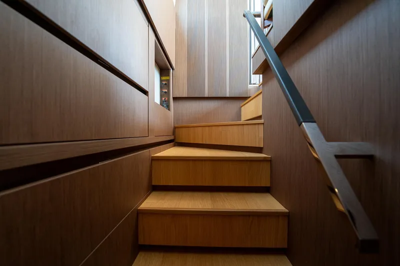  Yacht Photos Pics Wooden staircase inside 2023 Prestige X60 yacht, featuring sleek modern design and handrail.