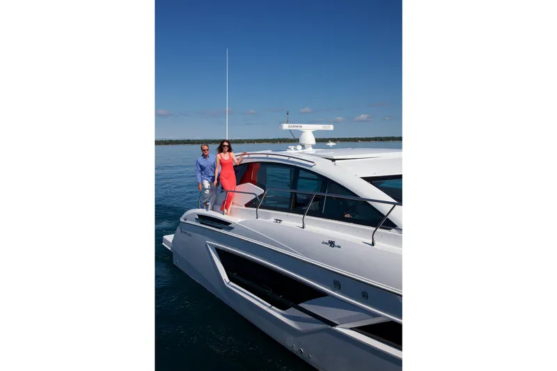  Yacht Photos Pics 2026 Cruisers Yachts 46 Cantius on water, with two people enjoying the deck.