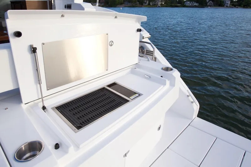  Yacht Photos Pics Luxury outdoor grill on 2026 Cruisers Yachts 46 Cantius, overlooking serene waters.