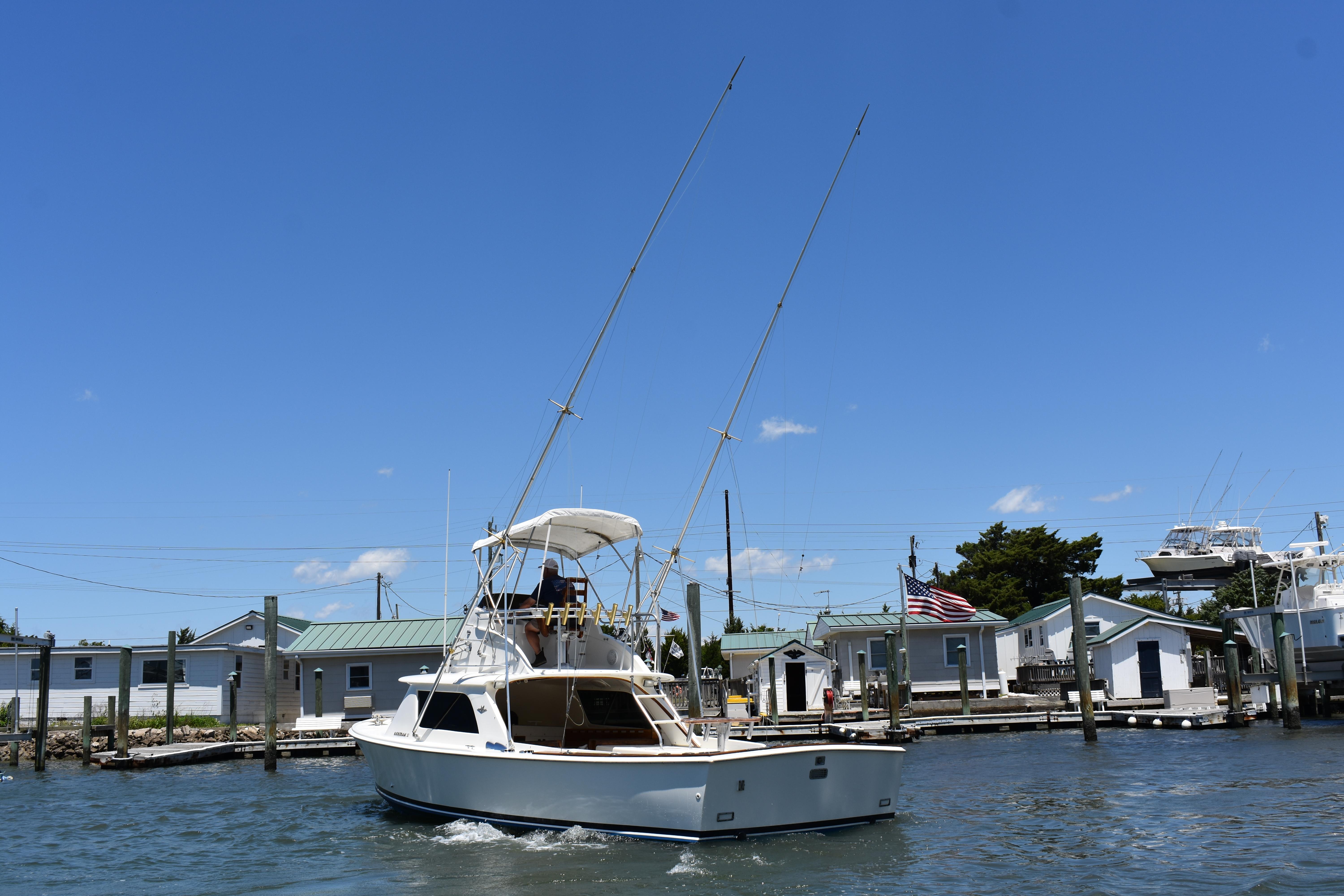 1965 Bertram 31 boat docked at a marina under a clear blue sky.