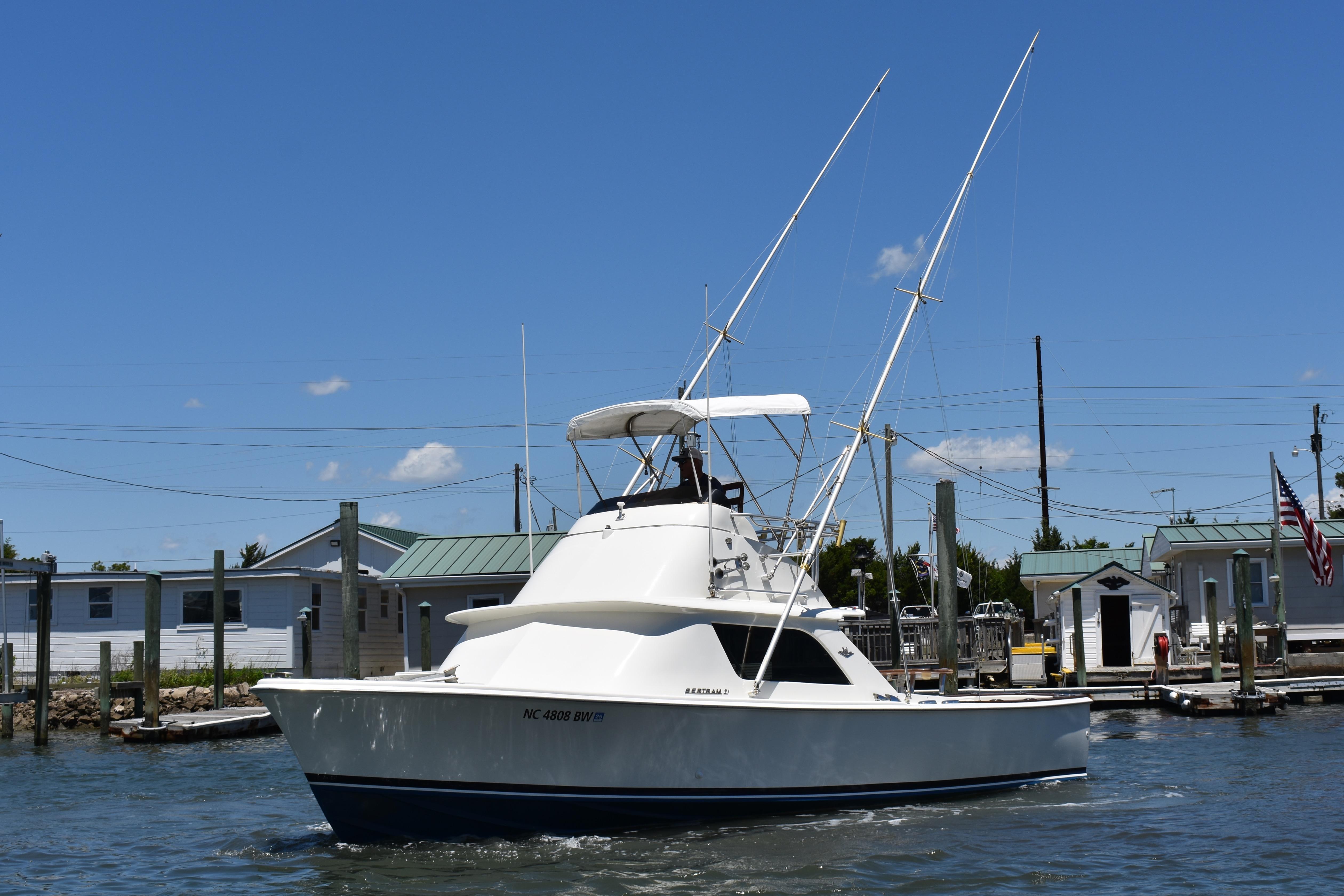 1965 Bertram 31 boat docked at a marina under a clear blue sky.