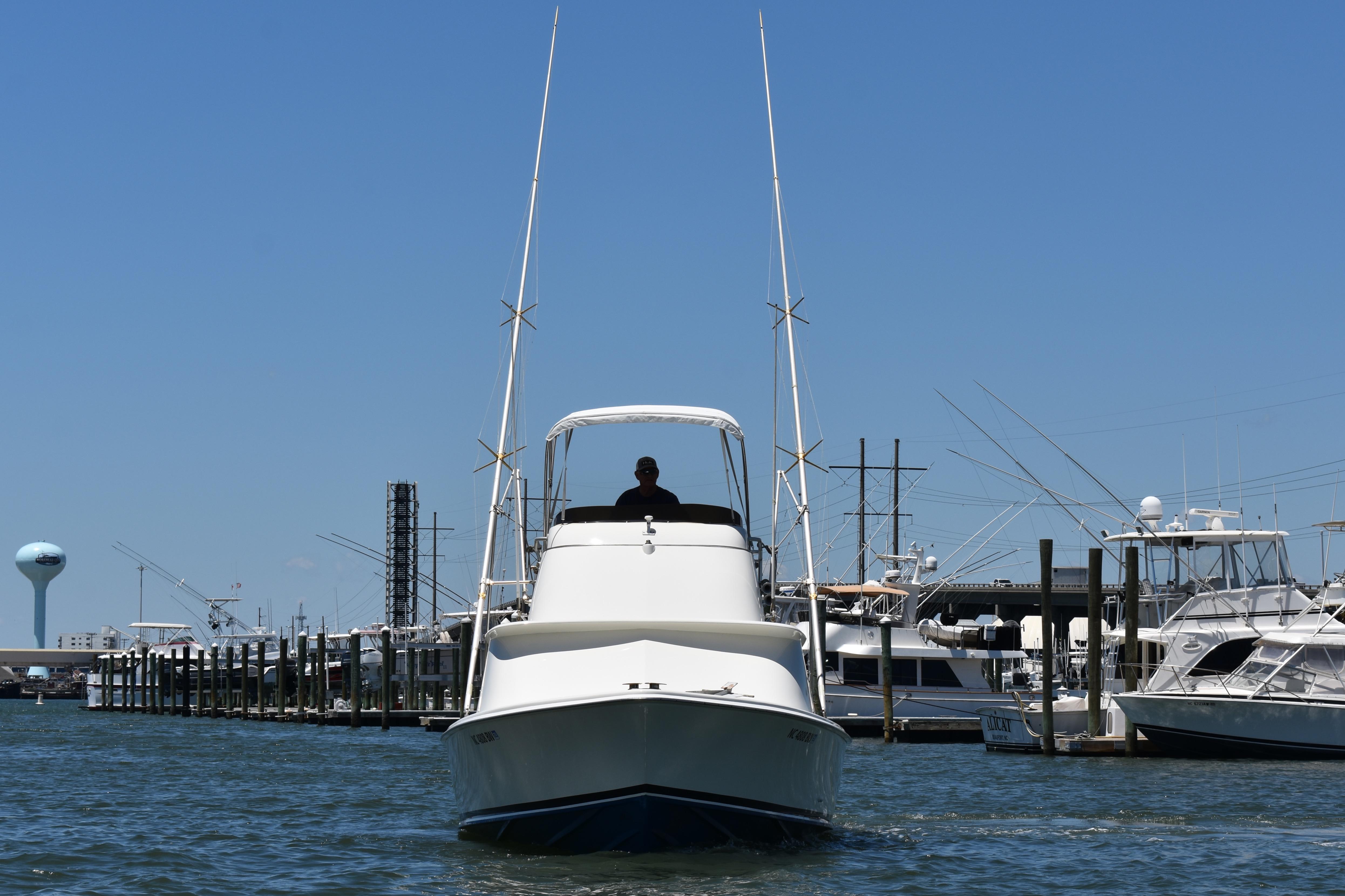 1965 Bertram 31 boat docked at marina under clear blue sky.