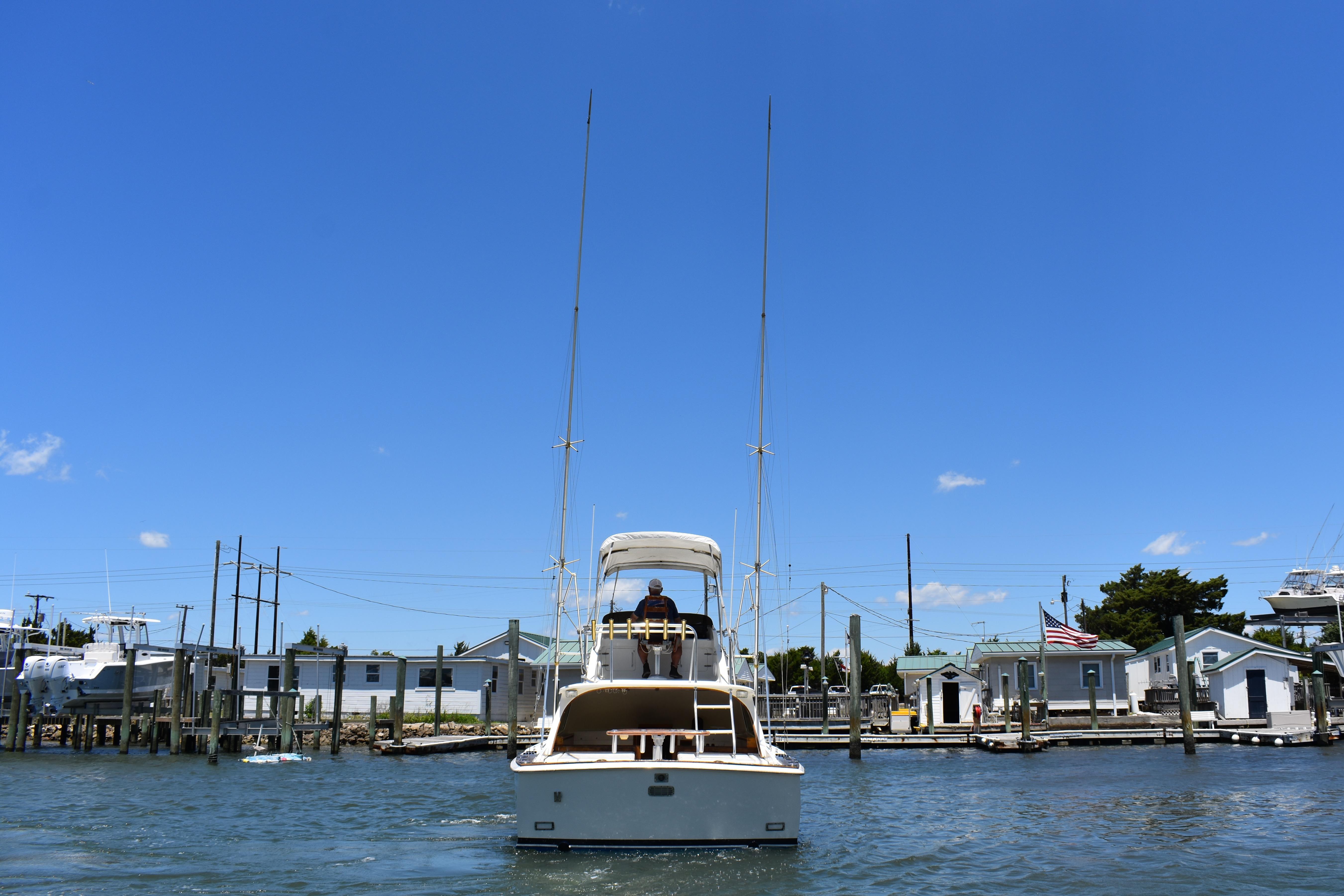 1965 Bertram 31 boat on water near docks under clear blue sky.