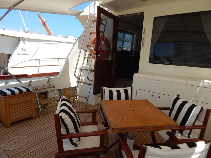  Yacht Photos Pics 1989 Hatteras 45 Convertible yacht deck with striped cushions and wooden table.